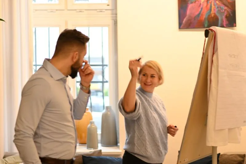Izabela udziela feedbacku uczestnikowi przy flipcharcie
